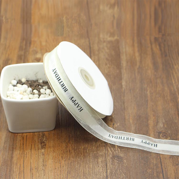 1" Happy Birthday Fabric Ribbon on a table against a vase